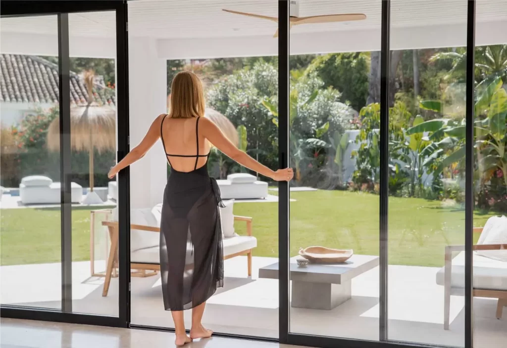 Mujer abriendo las puertas de vidrio panorámicas en un mirador.